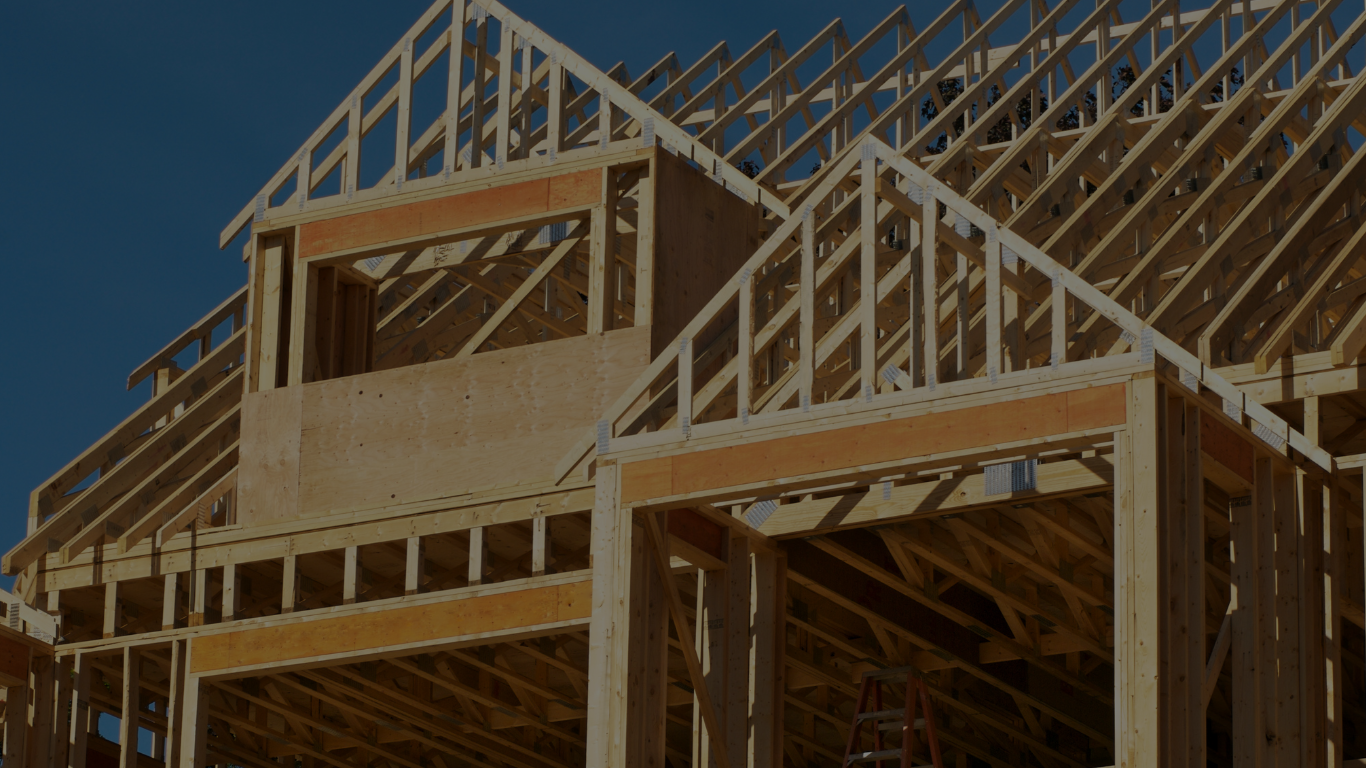 A photo of a home that is in the process of being built. The house is framed with raw lumber but not finished. 